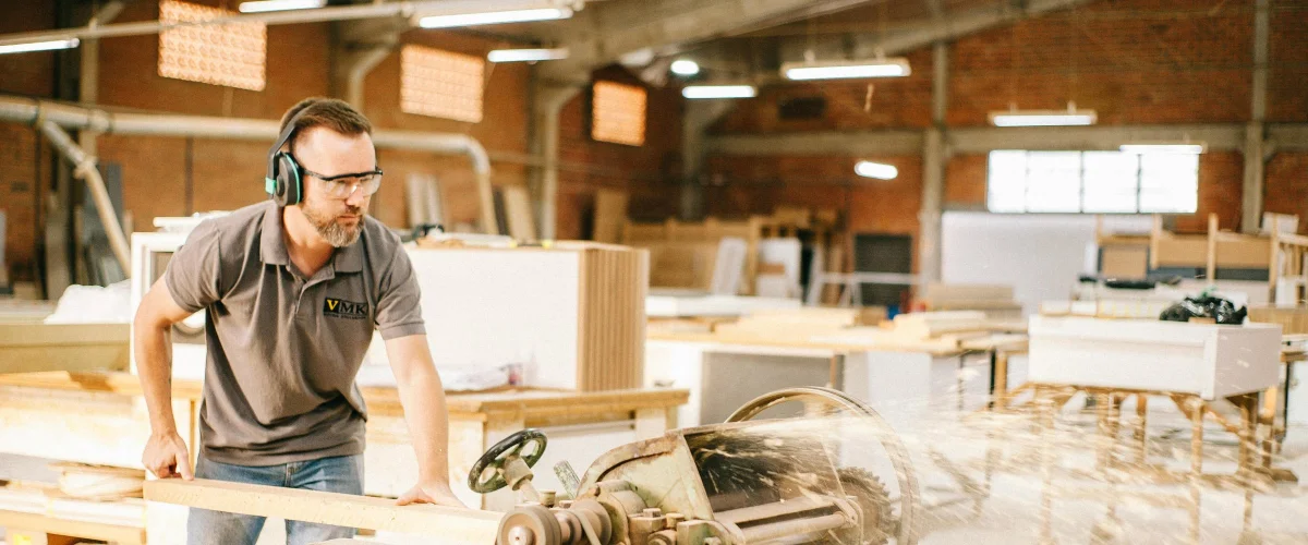 Craftsperson working with timber in a sunlit woodworking workshop